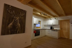 A kitchen with white cabinets, a wooden ceiling, and a painting of a deer on the wall. - Holiday home with 3 bedrooms (Lechbruck am See)
