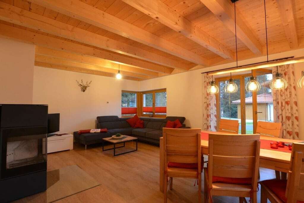 A cozy living room with a fireplace, a sofa, a dining table with chairs, and a large window with curtains.