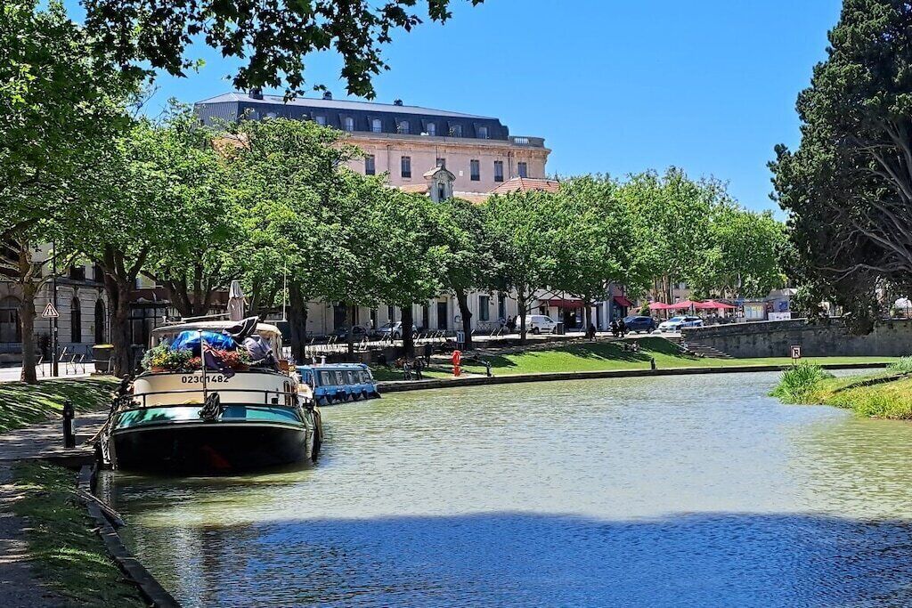 A canal with a boat, buildings, and trees.