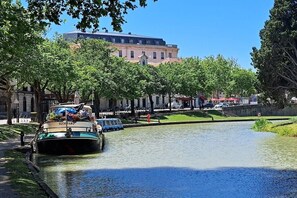 Kanava, jossa on vene, rakennuksia ja puita.