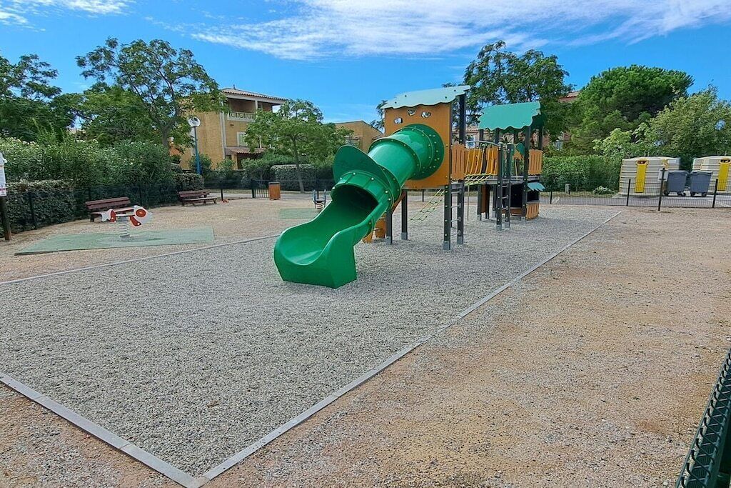 Uma área de recreação infantil com escorregador verde e estrutura de escalada.