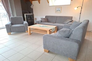 A living room with a grey sofa, a wooden coffee table, and a fireplace. - North Sea holiday home Hoffmeister (Wurster Nordseeküste)