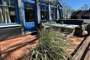 A patio area with a table and chairs, a blue building with large windows, and a potted plant. - Beach villa Miramare, apartment Seestern (Ostsee Bad Boltenhagen)