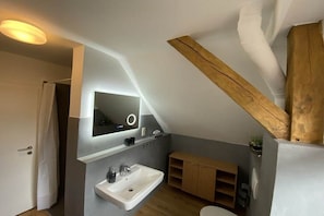 Un baño moderno con lavamanos integrado, un espejo y vigas de madera.