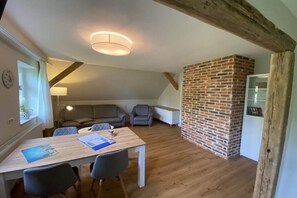 Ein gemütliches Zimmer mit einem Holztisch, zwei Stühlen, einer Backsteinwand und einer Deckenleuchte.