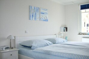 A bedroom with two beds, a bedside table with a lamp, a radio, and a wall-mounted TV. - Apartment Residence Baltic Sea Beach (Kühlungsborn)