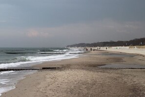 A beach with a sandy shore, waves, and a few people walking. - Apartment Residence Baltic Sea Beach (Kühlungsborn)