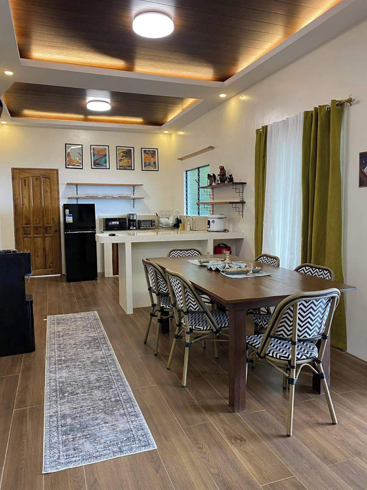 A modern kitchen with a dining area, wooden flooring, and a rug.