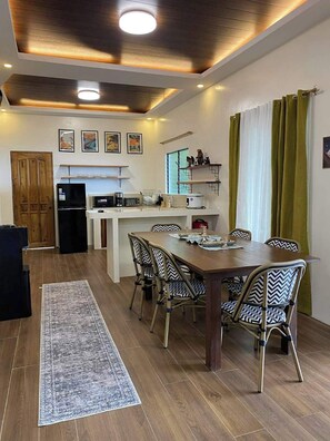 A modern kitchen with a dining area, wooden flooring, and a rug.