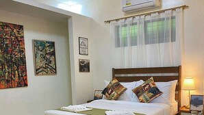 Ein Schlafzimmer mit einem Bett, einem Nachttisch, einer Klimaanlage und einem Fenster mit durchsichtigem Vorhang.