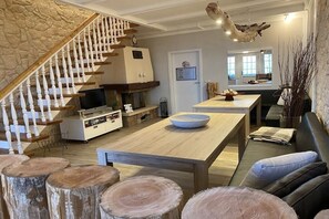 A modern living room with a wooden staircase, a fireplace, a dining area, and a view of the kitchen. - Holiday home "On the cliffs" Apt. 4 (Boltenhagen Redewisch)