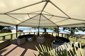 A covered outdoor seating area with a view of the sea, featuring wicker furniture and a fire pit. - Holiday home "On the cliffs" Apt. 4 (Boltenhagen Redewisch)