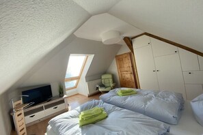 A bedroom with two beds, a TV, a wooden wardrobe, and a window. - Holiday home "On the cliffs" Apt. 4 (Boltenhagen Redewisch)