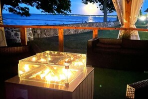 An outdoor seating area with a glass-top table and chairs, overlooking a body of water. - Holiday home "On the cliffs" Apt. 4 (Boltenhagen Redewisch)