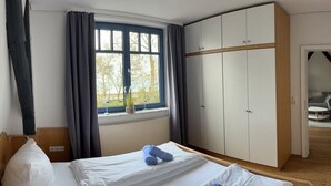 Habitación de hotel con dos camas, un armario grande, una ventana con cortinas y vistas al exterior.