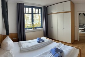 Habitación de hotel con dos camas, un armario grande, una ventana con cortinas y vistas al exterior.