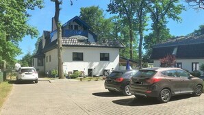 Una casa de dos pisos con entrada pavimentada y autos estacionados.