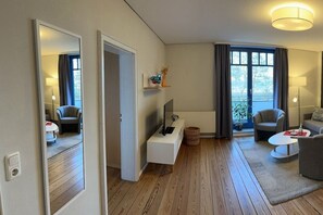 A modern living room with a flat-screen TV, a sofa, a coffee table, and a dining table. - Beach villa Miramare, apartment Seezunge (Ostsee Bad Boltenhagen)