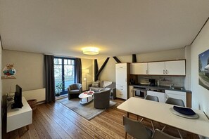 A compact living space with a kitchenette, a dining area, and a seating area with a view to the outdoors. - Beach villa Miramare, apartment Seezunge (Ostsee Bad Boltenhagen)