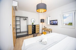 Ein modernes Schlafzimmer mit Bett, Kleiderschrank, Schreibtisch, Spiegel und Fernseher.
