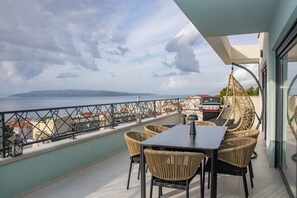 Ein Balkon mit Tisch und Stühlen, einem Grill und Blick aufs Meer.