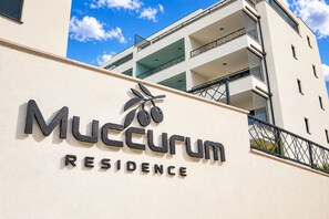 A building with a sign that reads 'Mucurum Residence' and a palm tree logo. - Modern Penthouse Helena with 3 BR, Pool, Sea View, Elevator & Garage (Makarska)