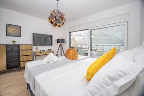 A modern bedroom with a large bed, a desk, a chair, a television, and a balcony with a view. - Modern Penthouse Helena with 3 BR, Pool, Sea View, Elevator & Garage (Makarska)