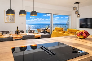 A modern dining area with a large table, chairs, and pendant lighting. - Modern Penthouse Helena with 3 BR, Pool, Sea View, Elevator & Garage (Makarska)