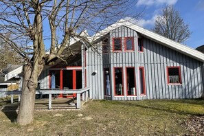 A two-story house with a sloped roof, red-framed windows, and a visible staircase leading to the entrance. - Holiday home IDA in the Mirow holiday park (Mirow-Granzow)