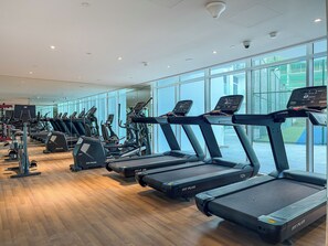 A gym with multiple treadmills, exercise bikes, and weight machines. - Stunning Studio | 12 Min to Mall of the Emirates (Dubai)