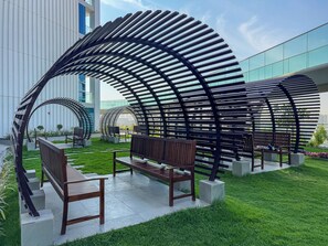 An outdoor seating area with benches and a modern metal structure. - Stunning Studio | 12 Min to Mall of the Emirates (Dubai)