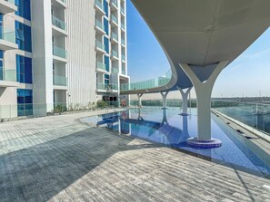 A modern building with a rooftop pool and a glass balustrade. - Stunning Studio | 12 Min to Mall of the Emirates (Dubai)