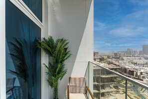 Ein Balkon mit Blick auf eine Stadtansicht, einem Blumentopf und einem Stuhl.