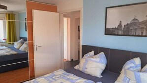 Un dormitori amb llit, armari, mirall i un quadre penjat a la paret.