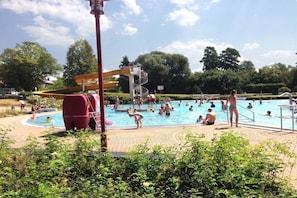 Ein Schwimmbeckenbereich mit Wasserrutsche und einer roten Konstruktion.