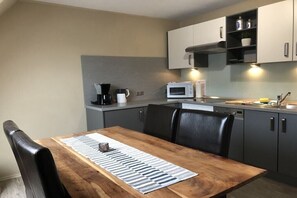Une cuisine compacte comprenant une table à manger, des chaises, un four à micro-ondes et une machine à café.