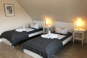 Una habitación con dos camas individuales, cada una con cabecera, mesitas de noche y lámparas.