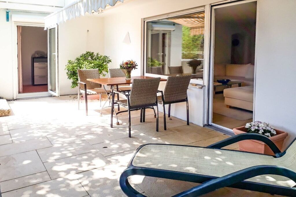Eine Außenpatio mit Esstisch, Stühlen und einer Liege.