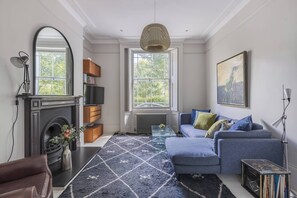 Ein Wohnzimmer mit Kamin, einer Couch, einem Couchtisch und einem großen Fenster.