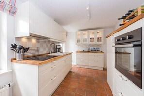Eine moderne Küche mit weißen Schränken, einer Holz Arbeitsplatte und einem eingebauten Backofen.