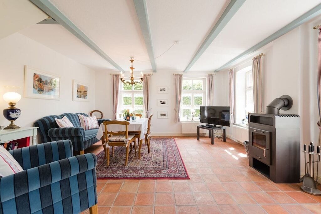 Una sala de estar con sofá, mesa de comedor, sillas, televisor y chimenea.