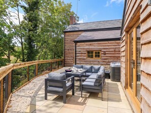A log cabin with a patio area featuring outdoor furniture and a table set for dining. - Bridge Farm (Wrexham)