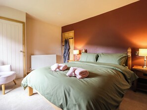 A hotel room with a bed, a chair, a radiator, and a lamp. - Bridge Farm (Wrexham)