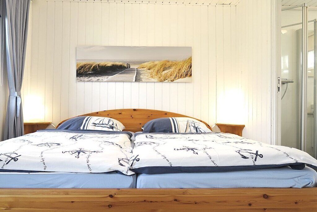 A bedroom with a wooden headboard, a bed with patterned bedding, two bedside tables, and a framed picture on the wall.