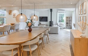 Un salon moderne avec un coin repas, comprenant une grande table en bois, des sièges confortables et une cheminée.