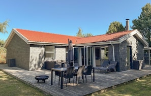A house with a red-tiled roof, a covered patio with a table and chairs, and a chimney.