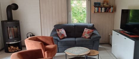 Un salon confortable avec un canapé, une petite table ronde, une cheminée et un téléviseur.