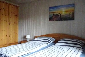 A bedroom with a bed, a nightstand, a lamp, and a painting on the wall. - Holiday home with 2 bedrooms (Mirow - Granzow)