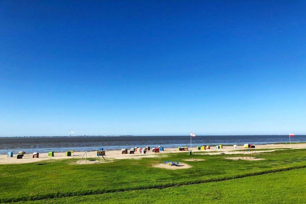 Une plage avec des cabanes colorées et un ciel bleu azur.