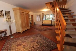 A spacious living area with a wooden staircase, a sofa, and a large rug. - Holiday apartment with 1 bedroom (Krummhörn - Greetsiel)
